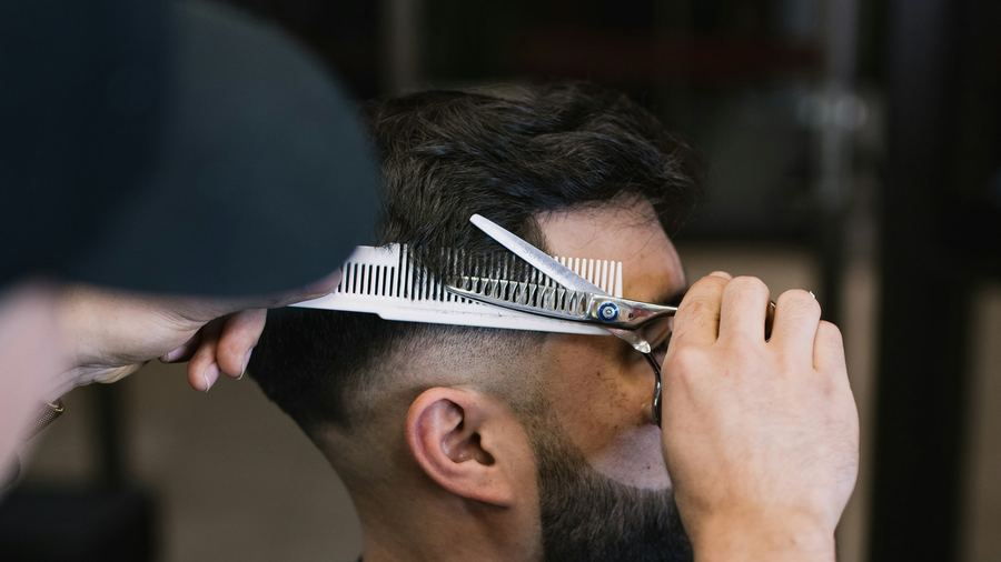 Scissors and comb working through the top of a haircut