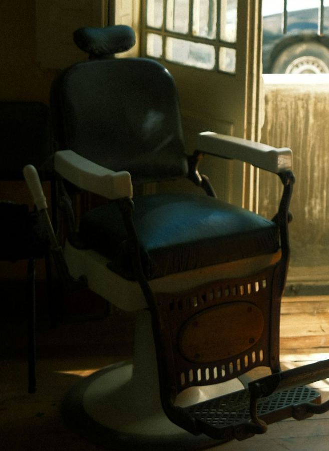A vintage barber's chair sitting in the light of the front window
